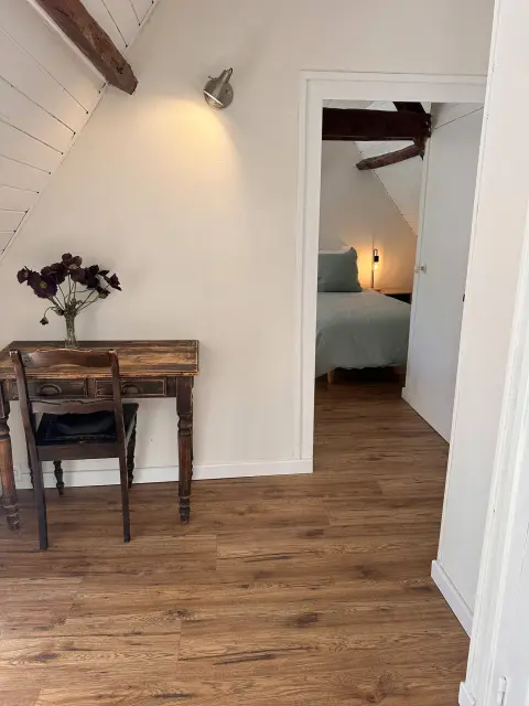 Een houten bureautje op de overloop, met doorkijk naar de kamer met eenpersoonsbedden